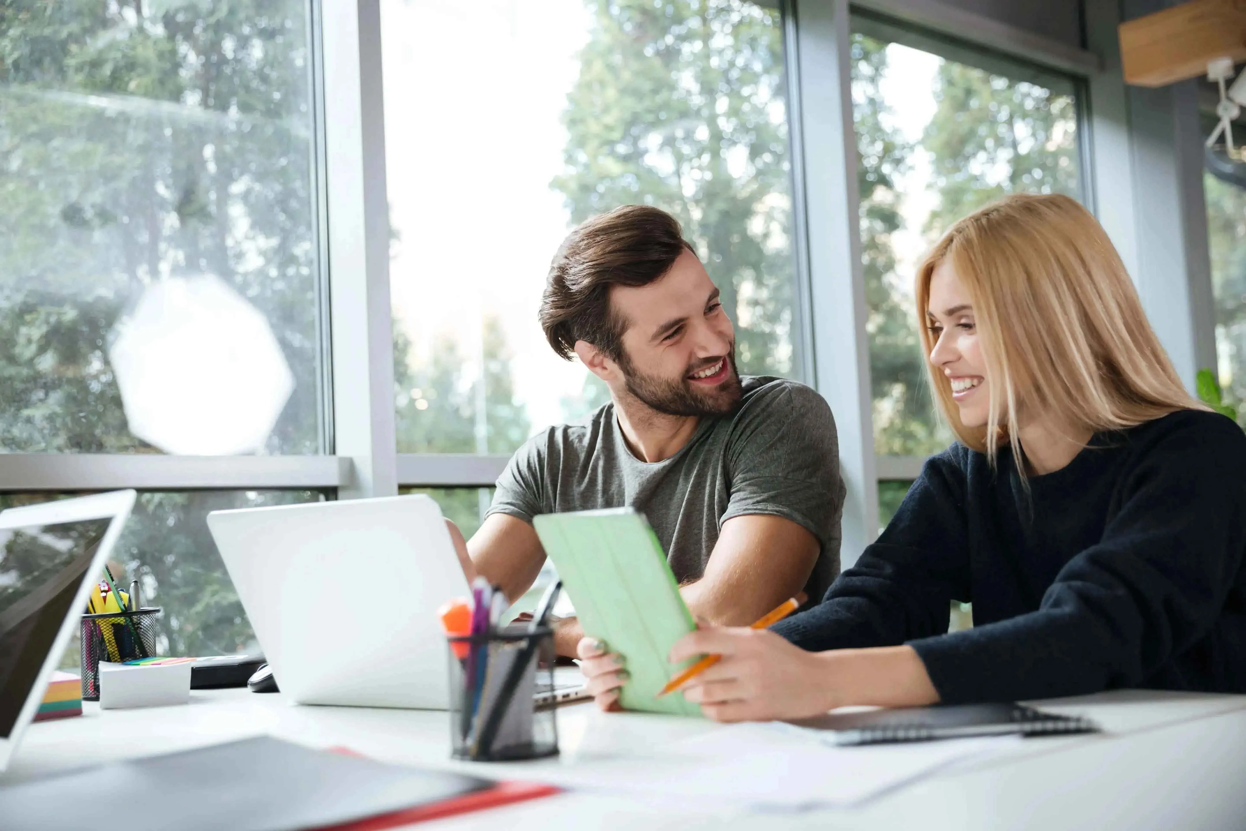 smiling-young-colleagues-sitting-office-coworking.webp